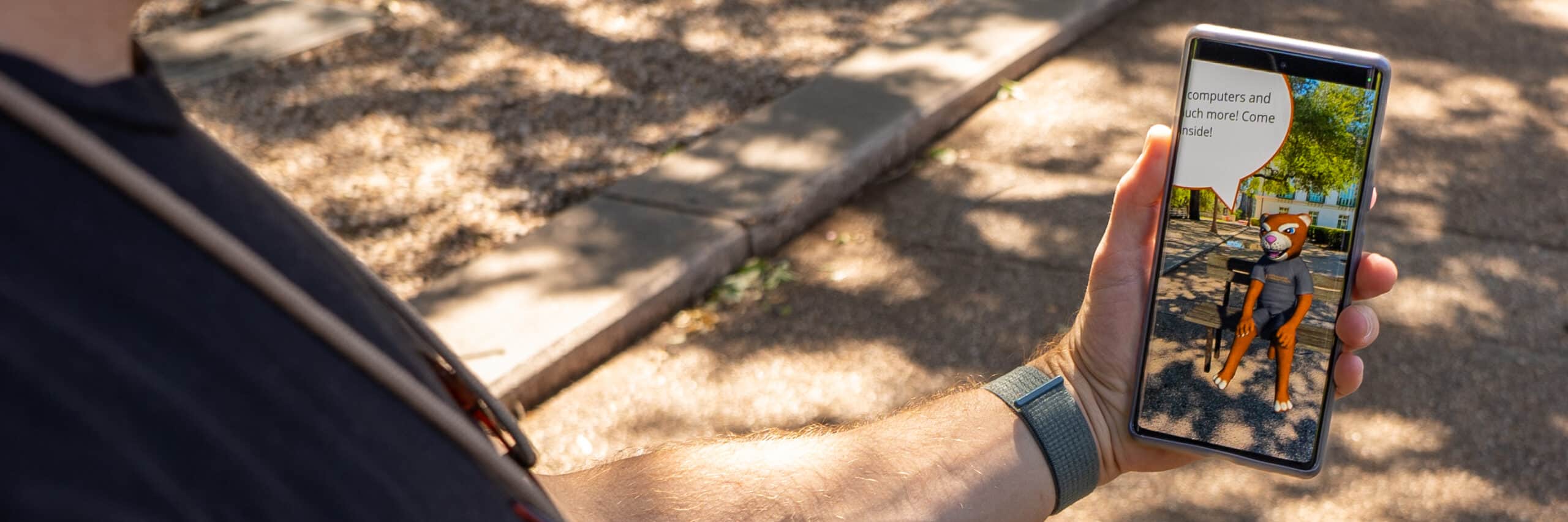 a man holding a phone using the SMCC AR feature in the Cougy Campus mobile app